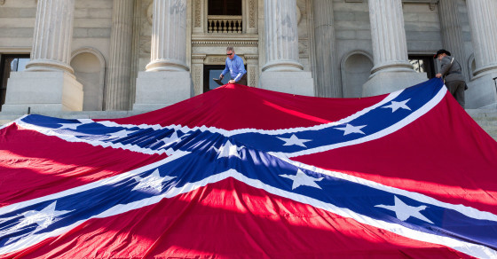 COLUMBIA, SC - MAY 02: Confederate re-enactors position a gigantic Confederate flag on the steps of the South Carolina State Capitol building on May 2, 2015 in Columbia, SC. Confederate Memorial Day is a official state holiday in South Carolina and honors those that served during the Civil War. (Photo by Richard Ellis/Getty Images)